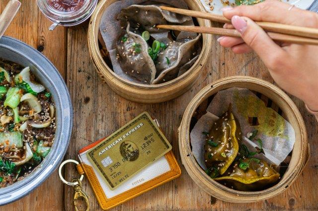 A few different Asian foods on a table with a credit card between them. 