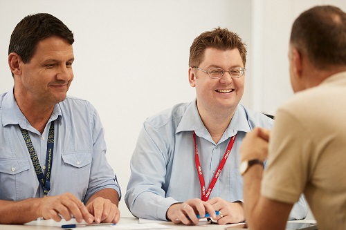 Two men sit next to each other across from another man