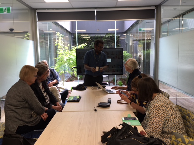 A VA staff members gives a group of people around a table a lesson about the internet