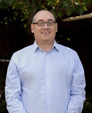 Vision Australia GM Commercial Services Michael Linke is smiling at the camera. He has glasses and is wearing a light blue shirt.