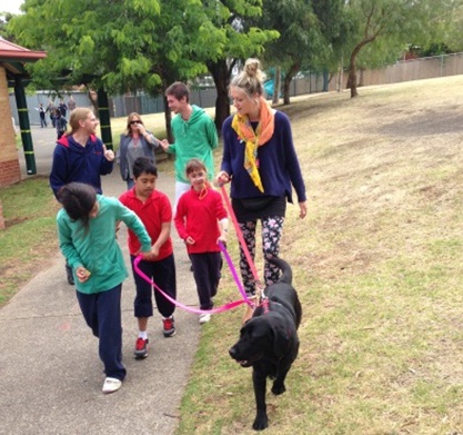 A group of children walk with Faith the labrador