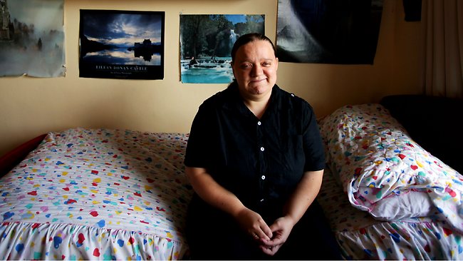 Katie is photographed sitting on a bed 