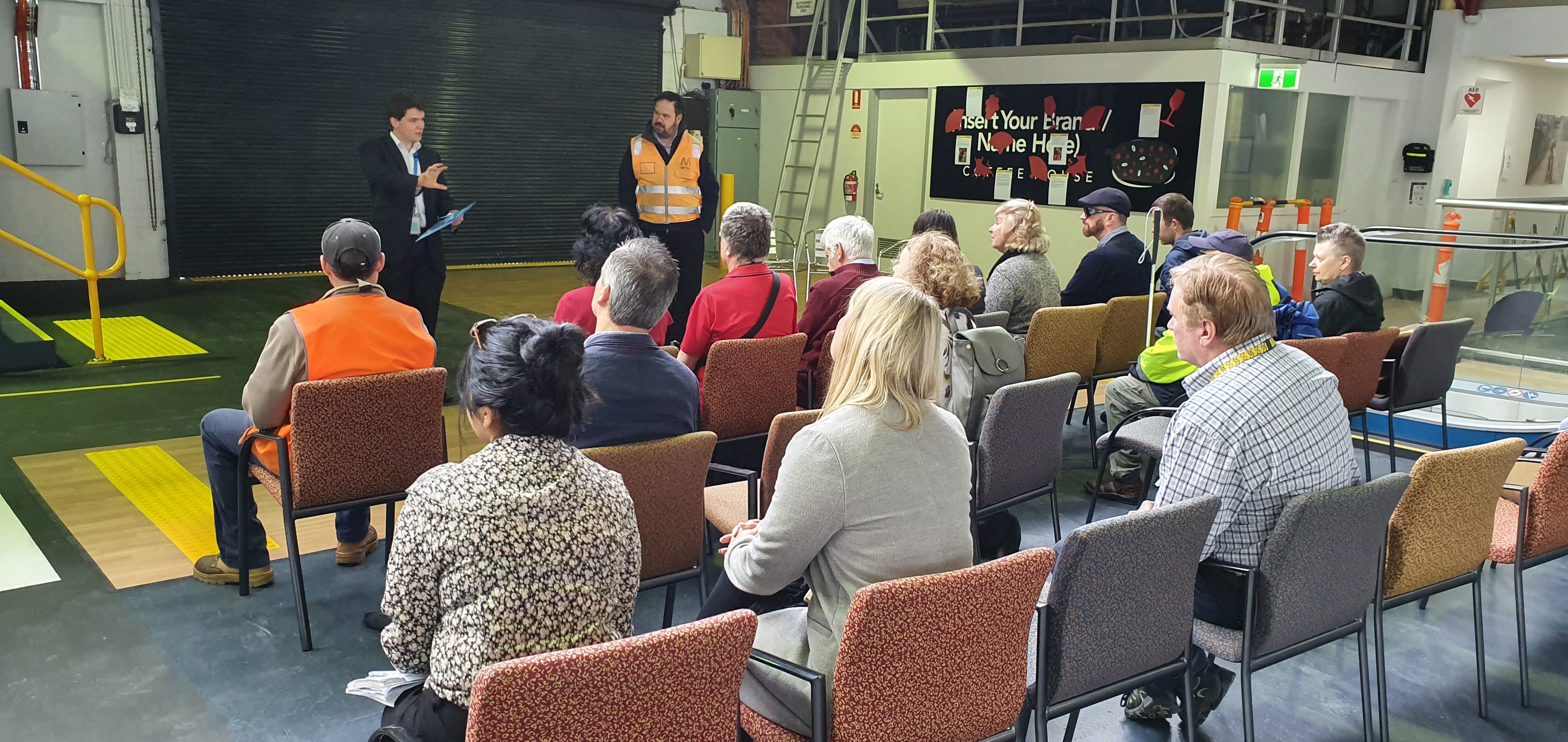 "Clients sit in chairs listening to Metro Trains staff explaining the features they will be trialing."