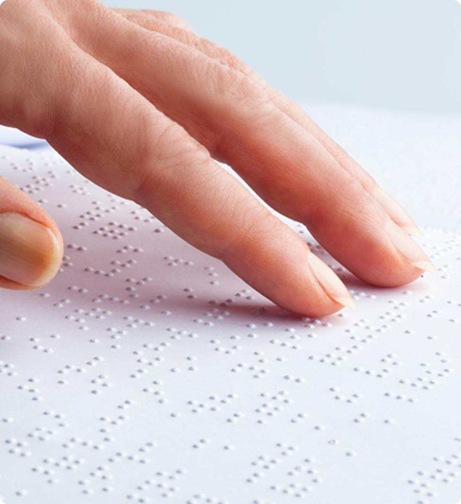 A close up of an adult hand reading braille