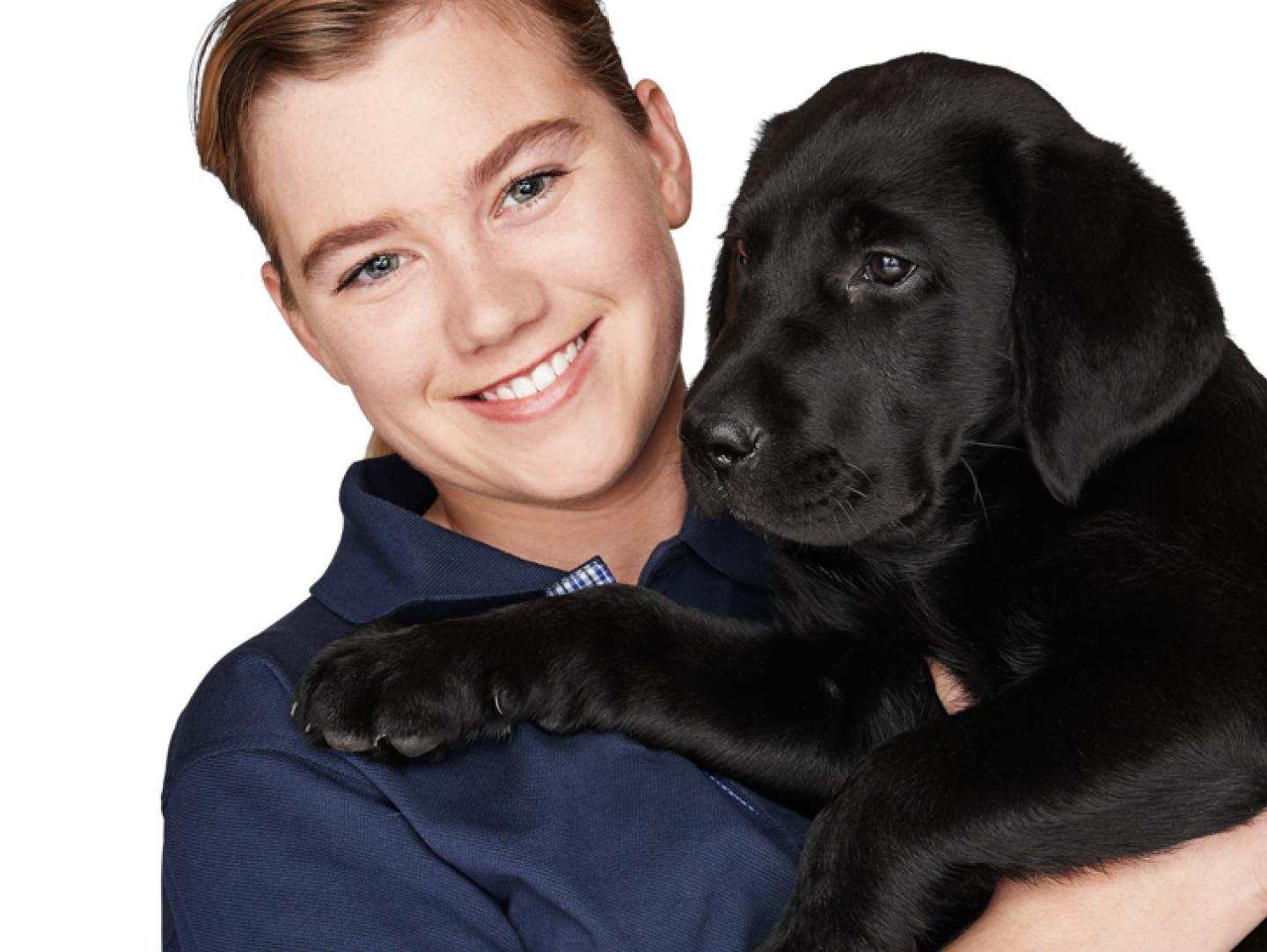 Vision Australia staff member holds a seeing eye dog puppy in her arms