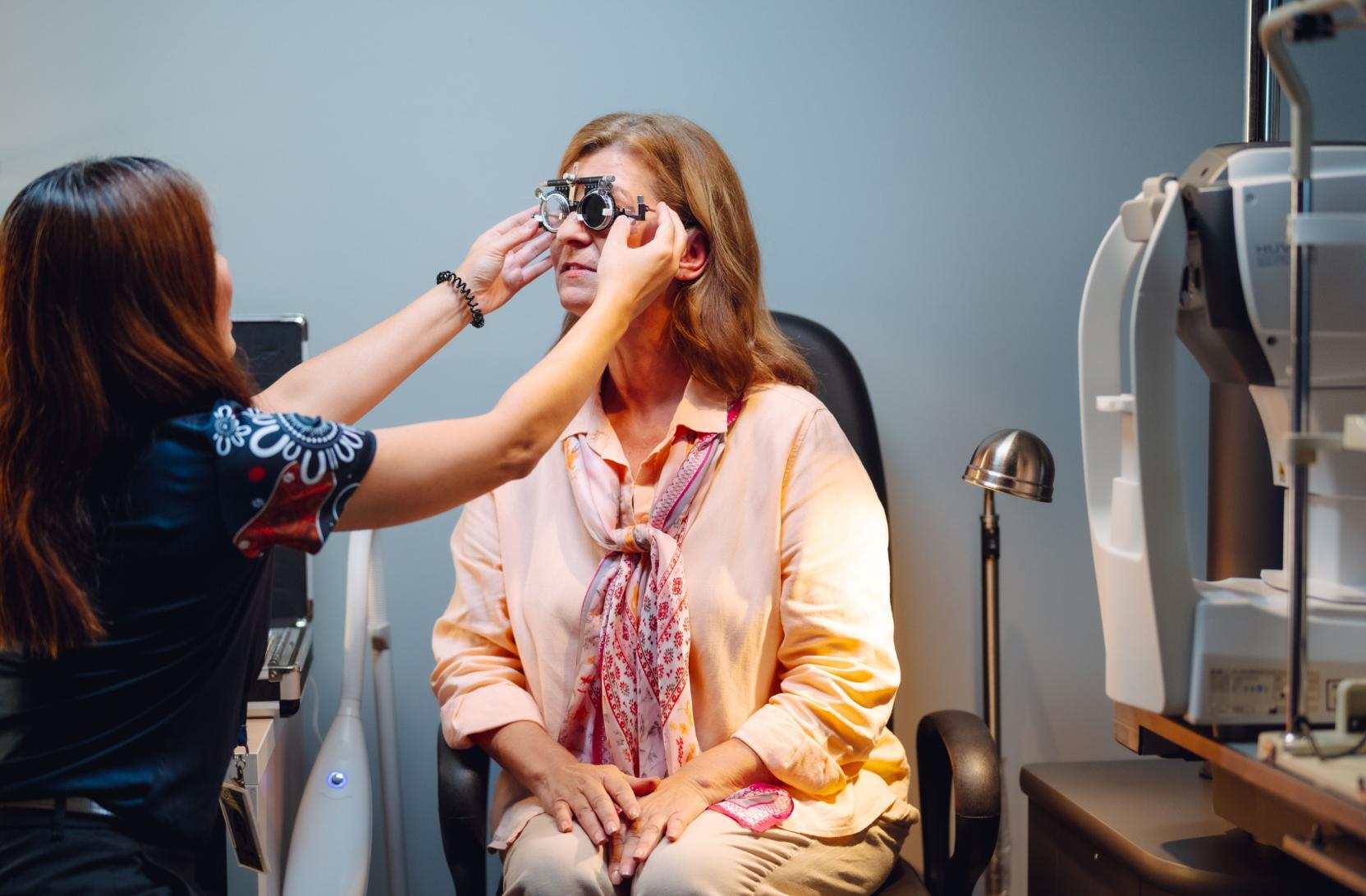 A Vision Australia specialist fits a pair of goggles on a client during an eye test.